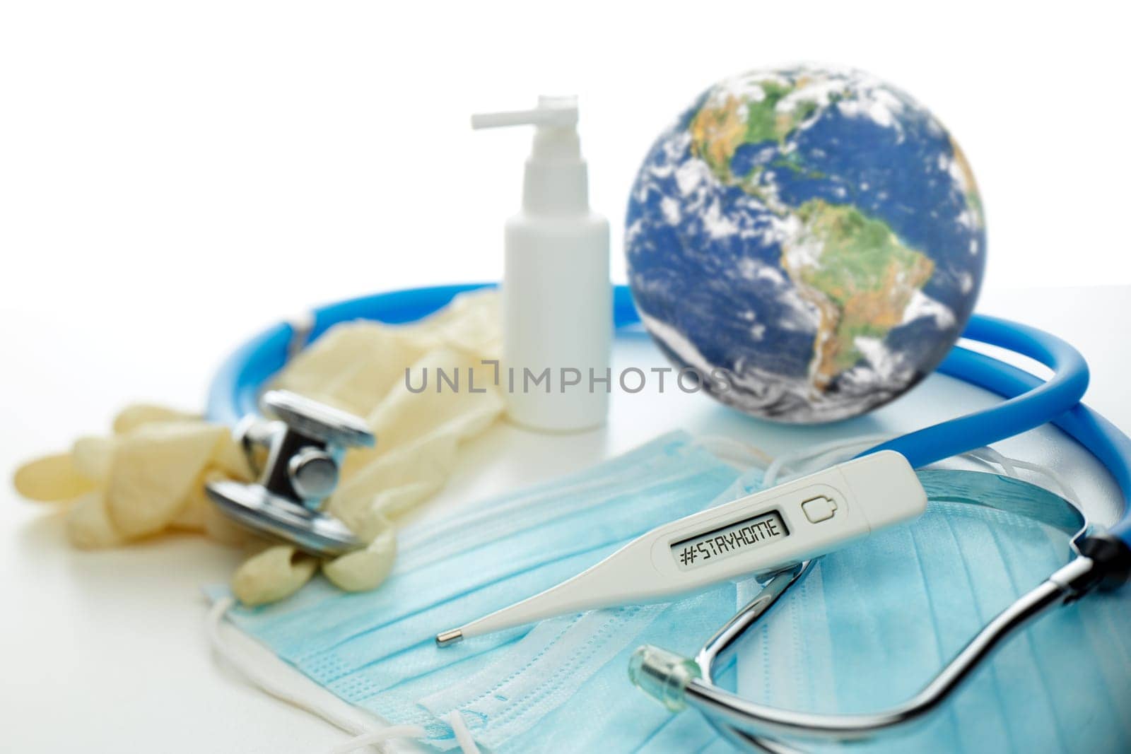 COVID-19. World globe with stethoscope, medical masks, sanitizer, thermometer on white background. Global quarantine,  coronavirus. Elements of this image furnished by NASA. Selective focus on thermometer