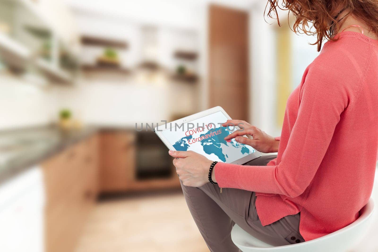 A woman looks into a tablet and watches information for coronavirus in home.