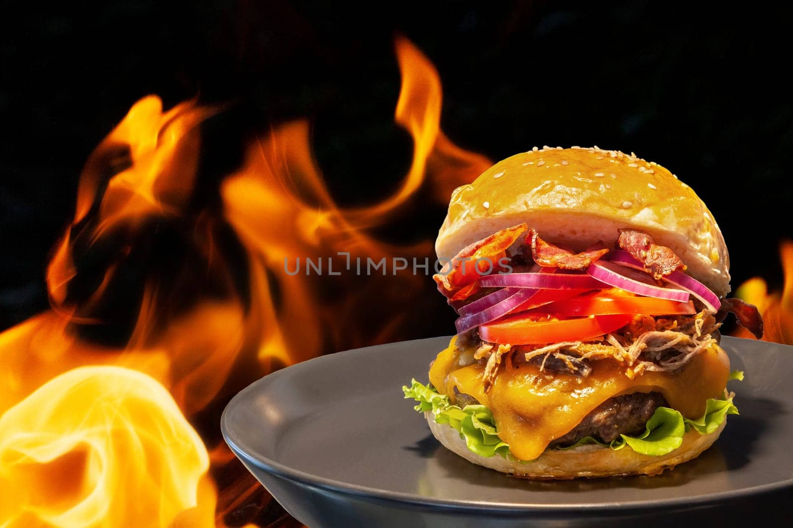 Close-up of home made burgers with fire flames and black background