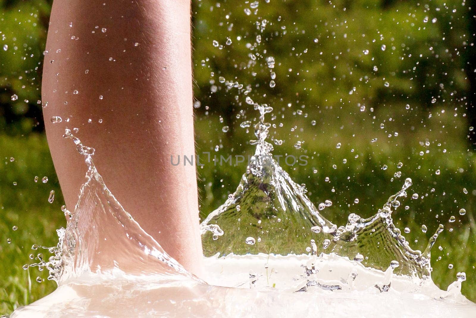 Little boy and splash of water in the summer garden - detail shot