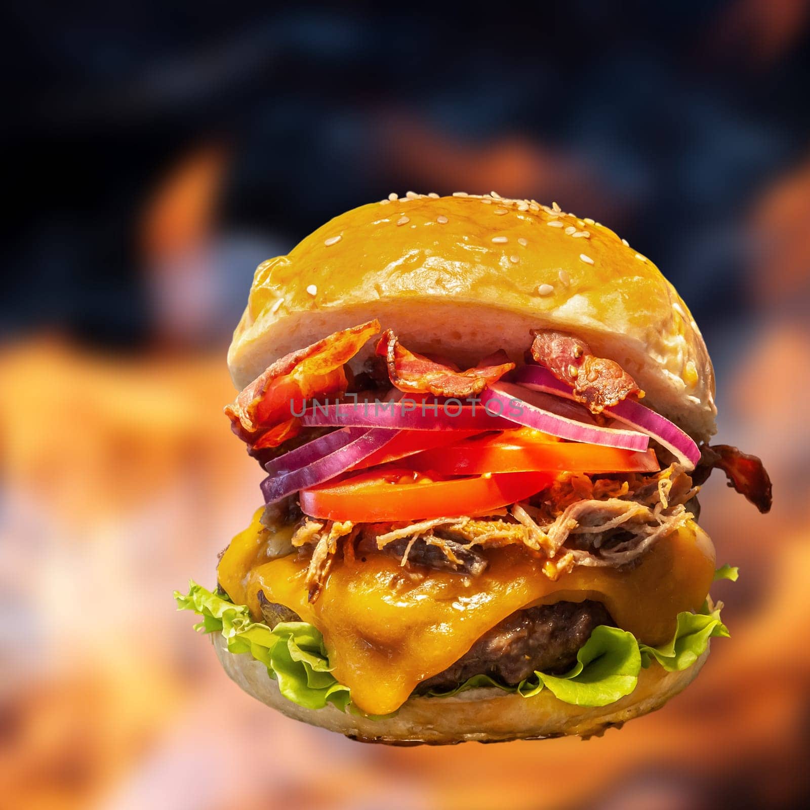 Close-up of home made burgers with fire flames and black background