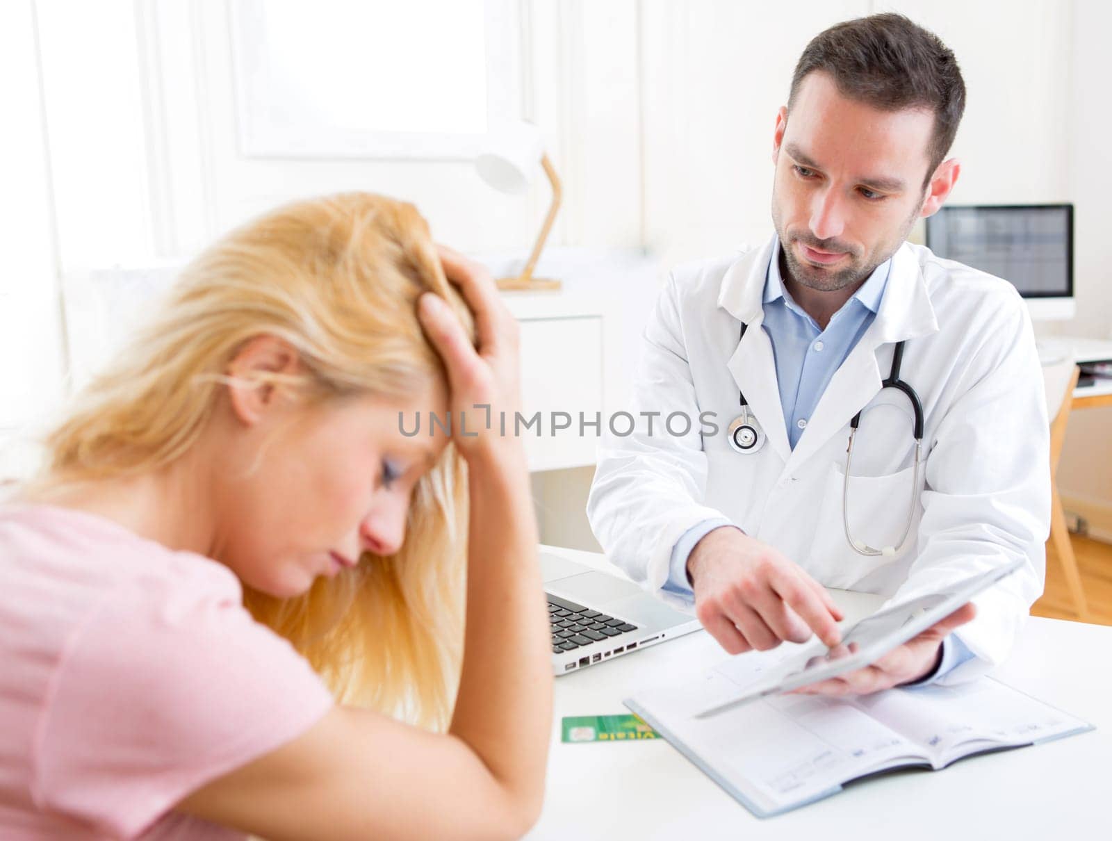 View of a Young doctor showing results on tablet to patient