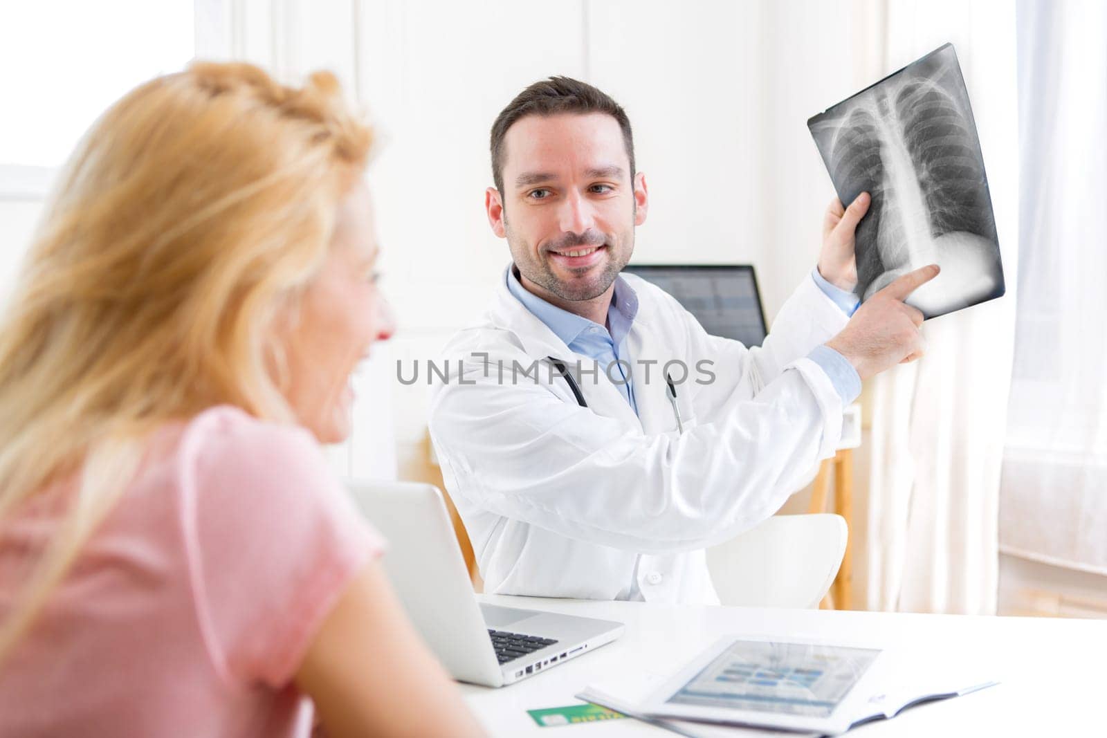 View of a Young attractive doctor analysing X-ray with patient