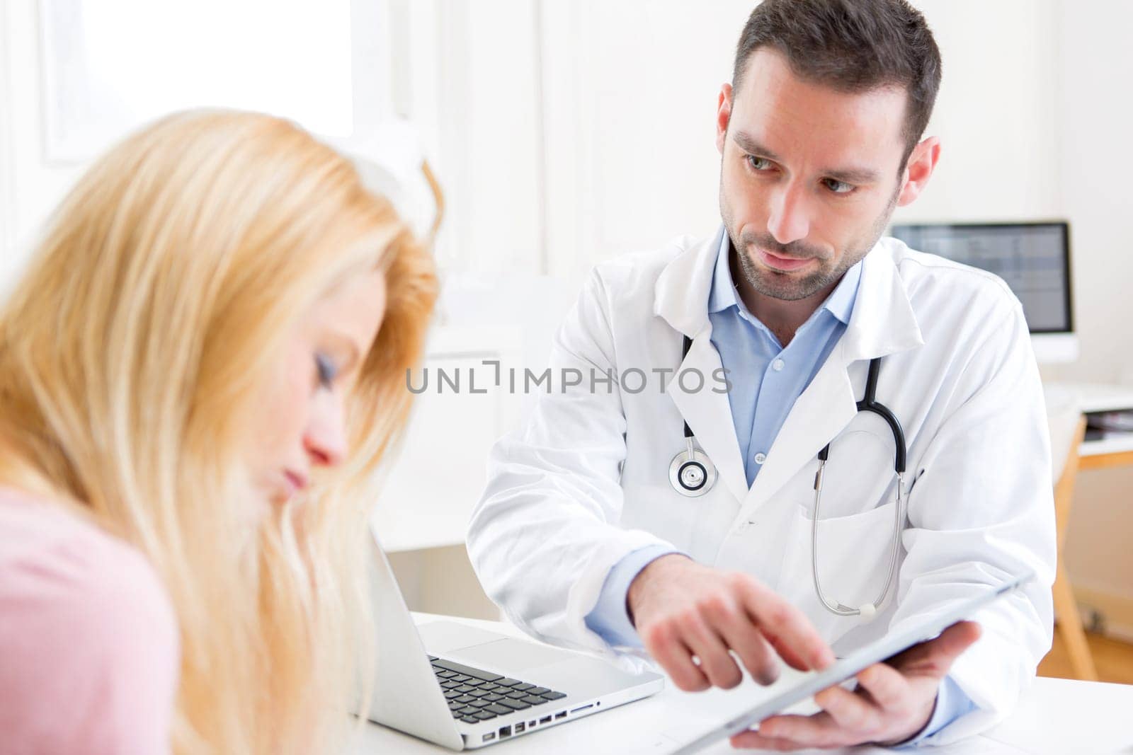 View of a Young doctor showing results on tablet to patient