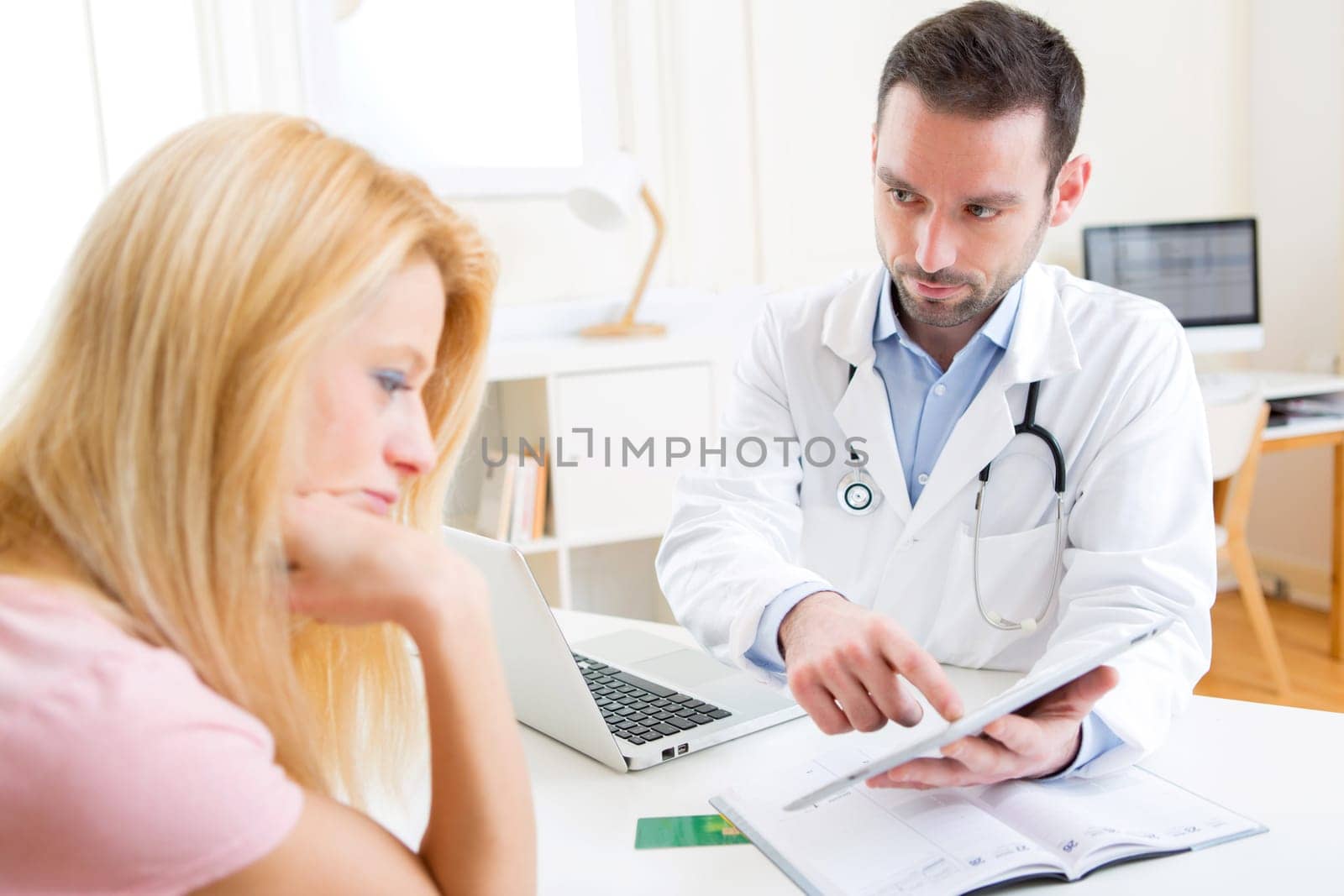 View of a Young doctor showing results on tablet to patient