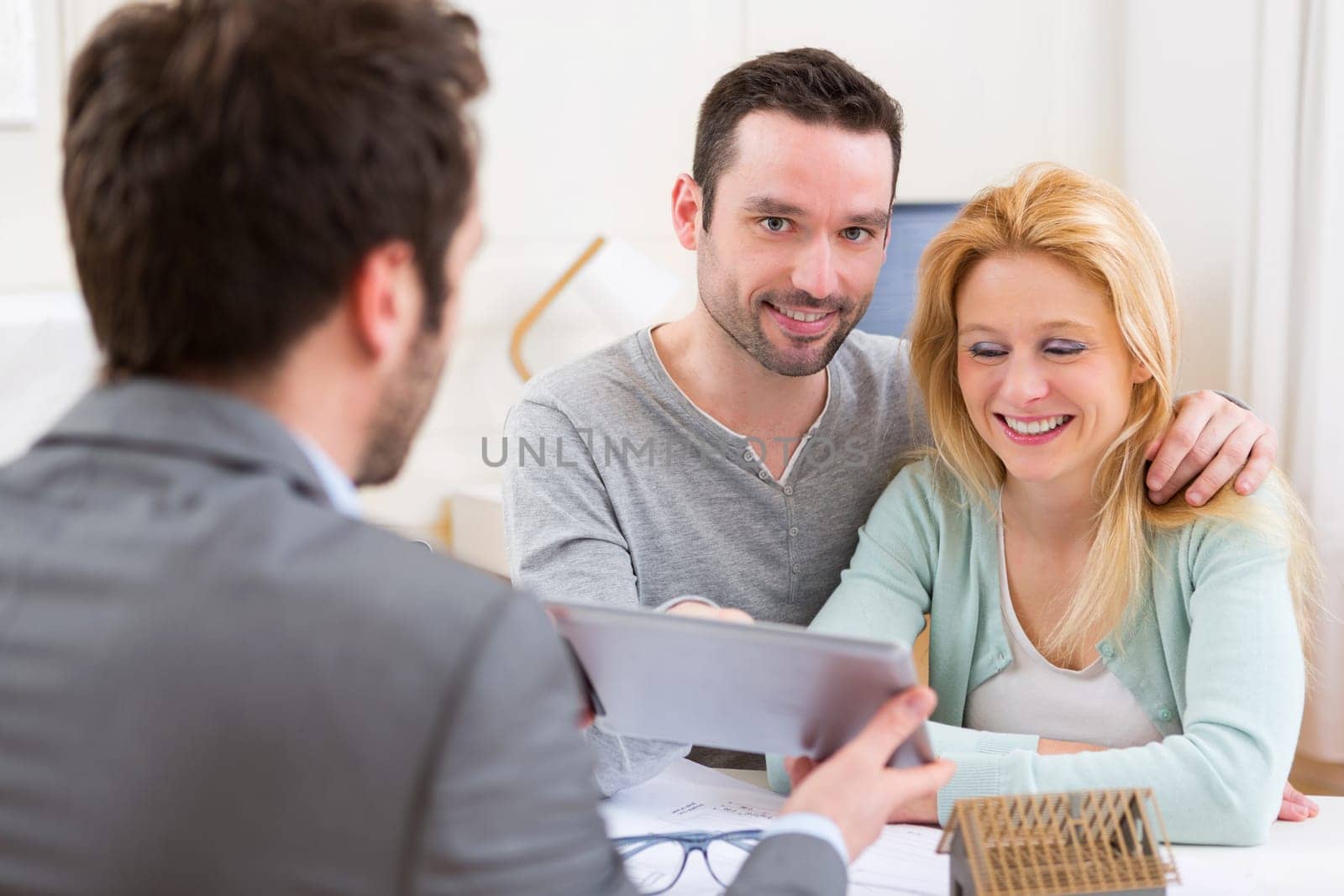 View of a Real estate agent present project on tablet to a young couple