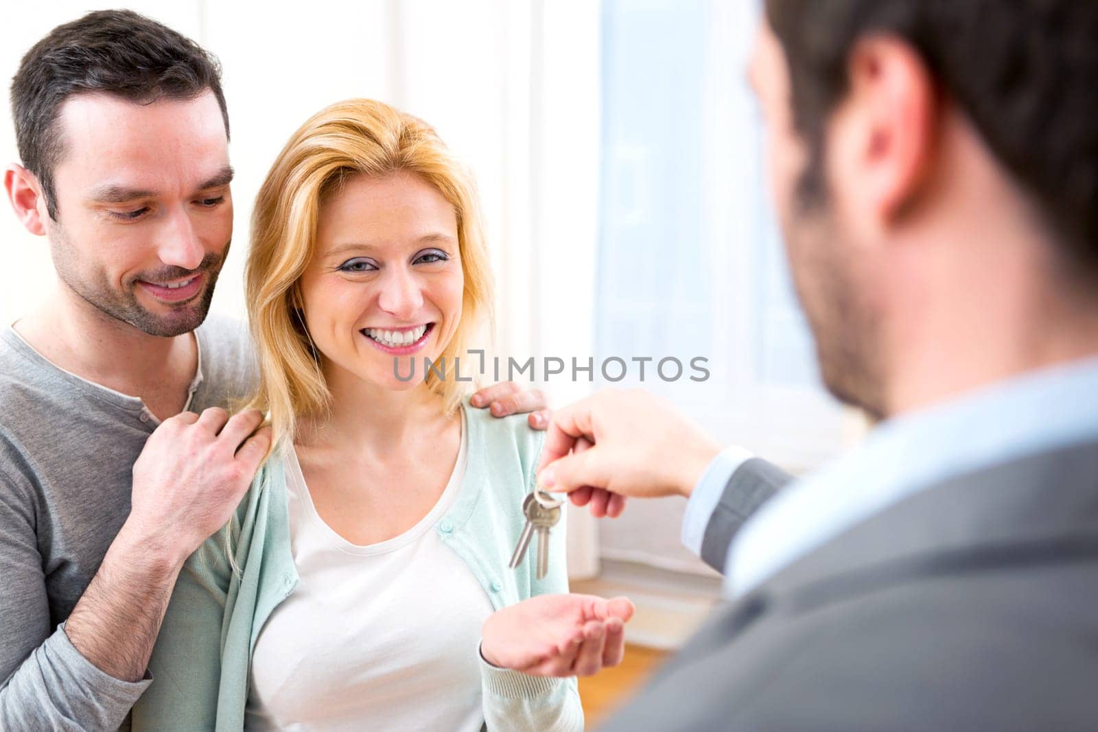 View of Real estate agent delivers keys of new house to young couple