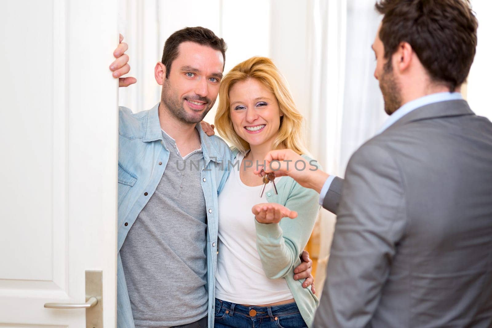 View of a Real estate agent delivers keys of new house to young couple