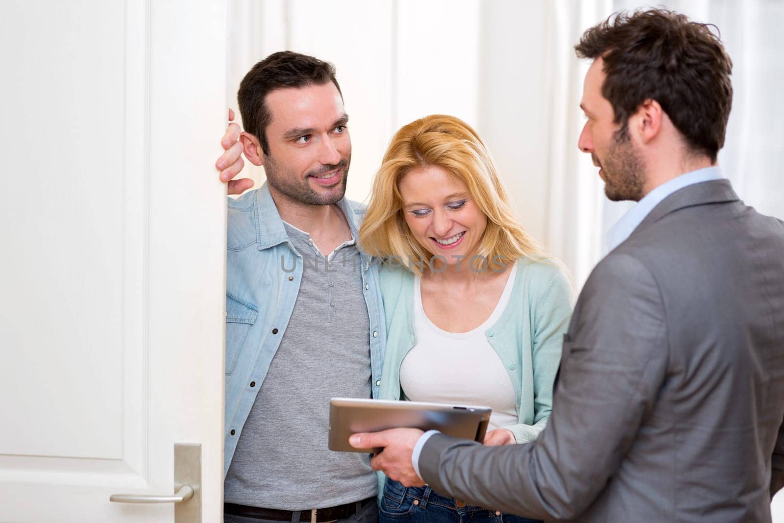 View of a Real estate agent present project on tablet to a young couple