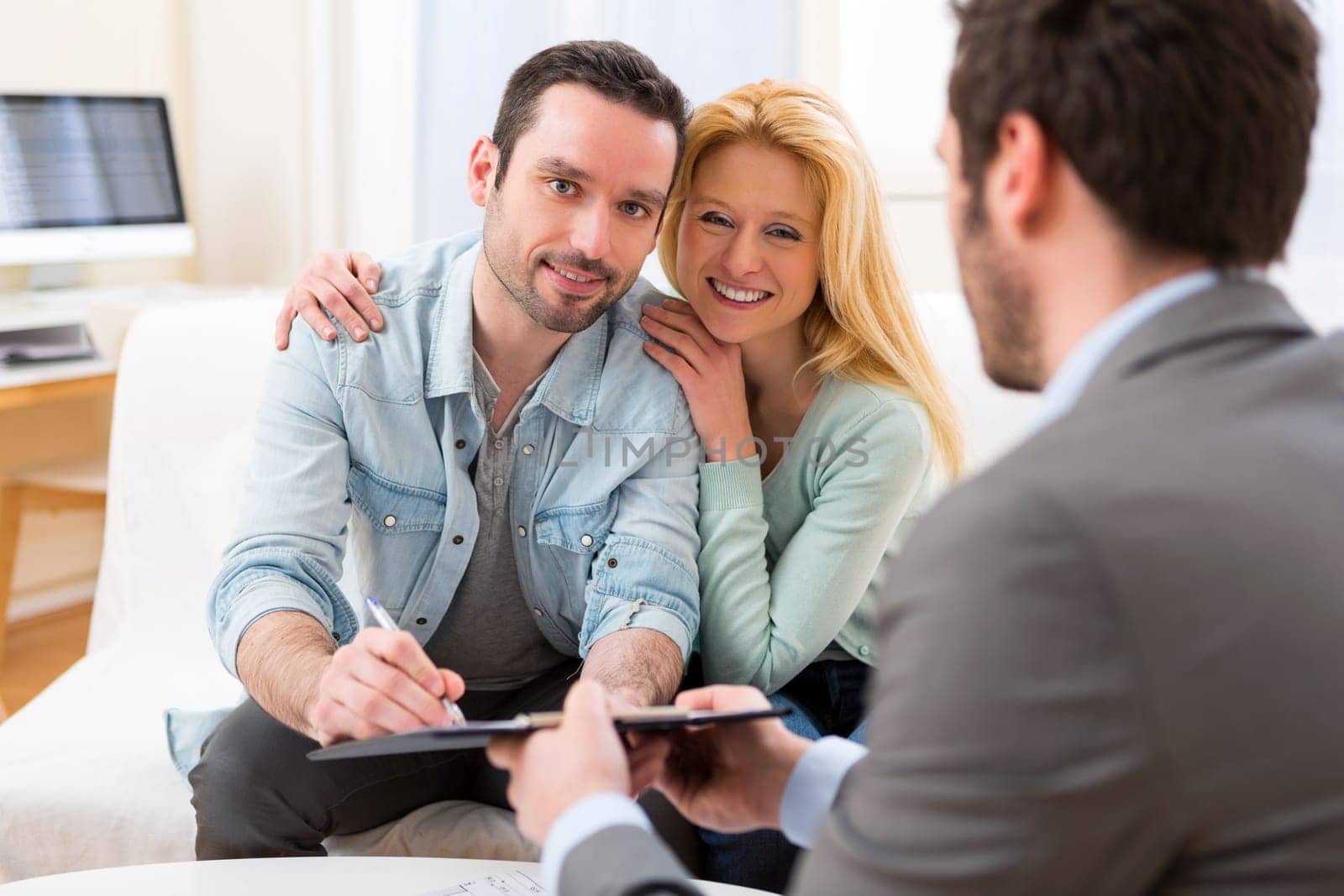 View of Young attractive couple signing contract with real estate agent