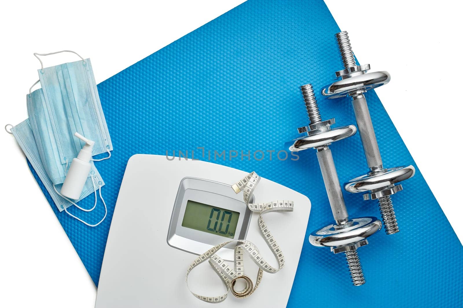 Sport equipment, scales, medical masks and sanitizer on white background. Top view, copy space. Fitness.  Isplation period. Weight and health control during quarantine. Concept of covid or coronavirus