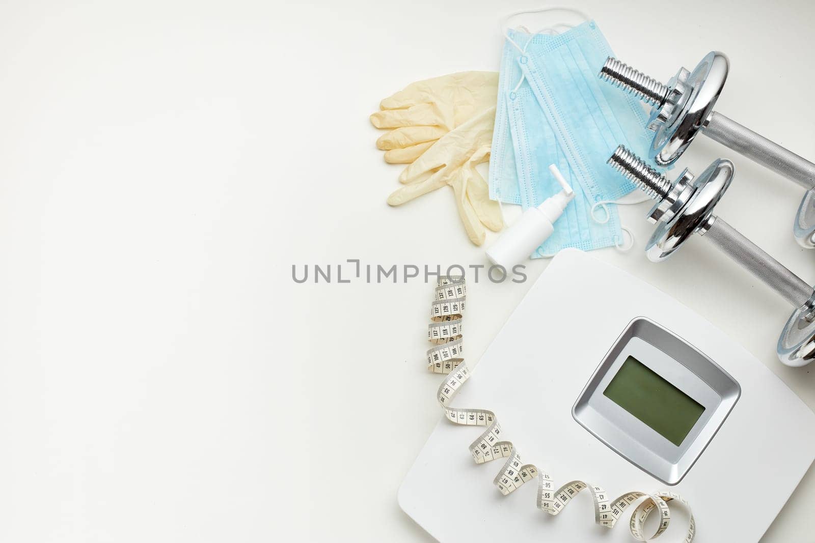 Sport equipment, scales, medical masks and sanitizer on white background. Top view, copy space. Fitness.  Isplation period. Weight and health control during quarantine. Concept of covid or coronavirus