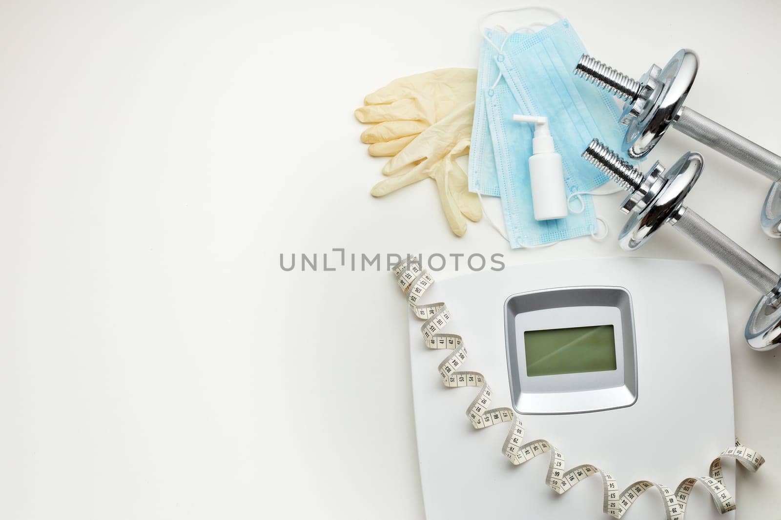 Sport equipment, scales, medical masks and sanitizer on white background. Top view, copy space. Fitness.  Isplation period. Weight and health control during quarantine. Concept of covid or coronavirus