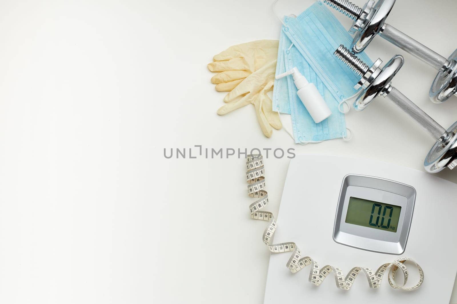 Sport equipment, scales, medical masks and sanitizer on white background. Top view, copy space. Fitness.  Isplation period. Weight and health control during quarantine. Concept of covid or coronavirus