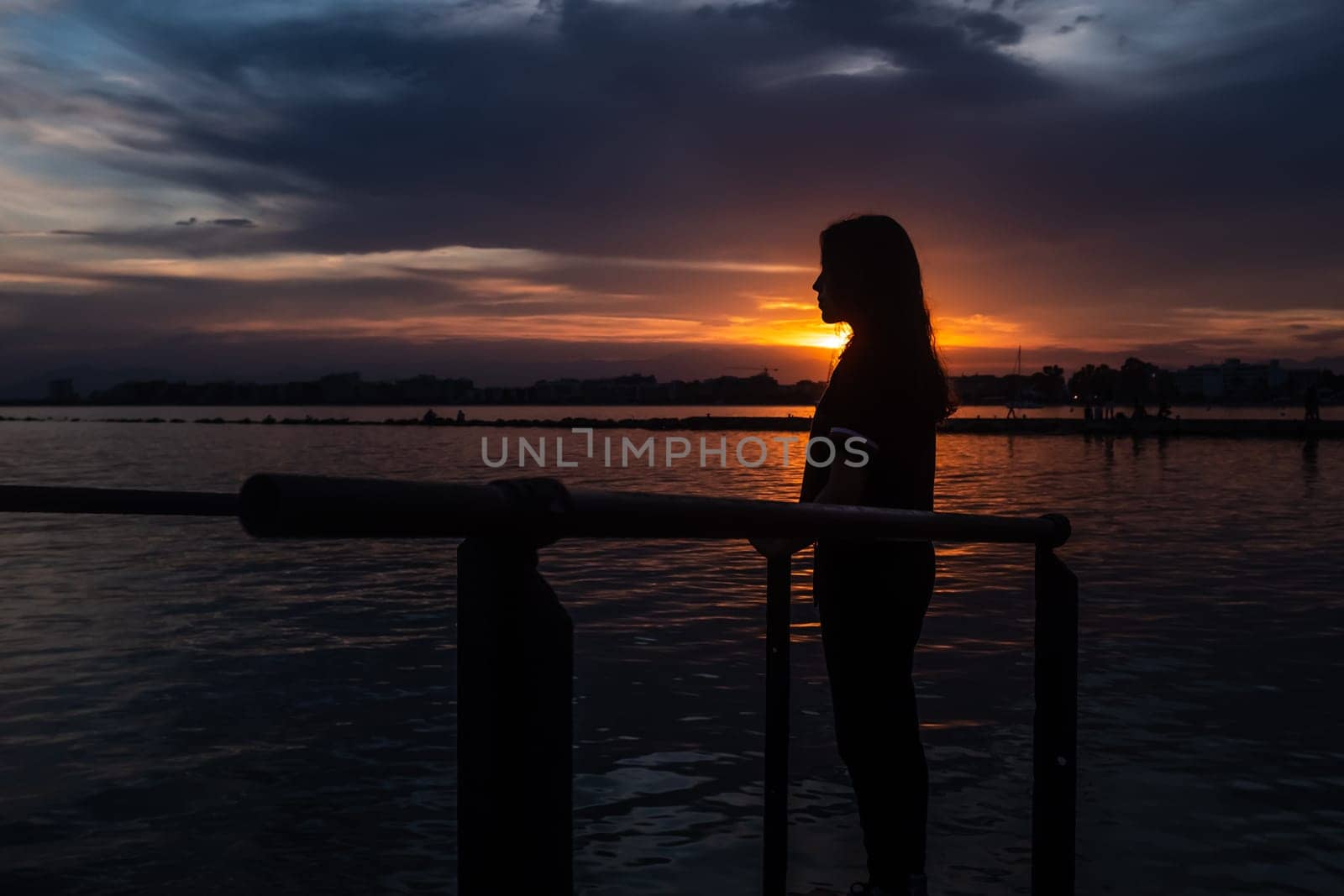 Young teenage girl with long hair at sunset beach looking in the distance. Concepts of introspection and contemplation.