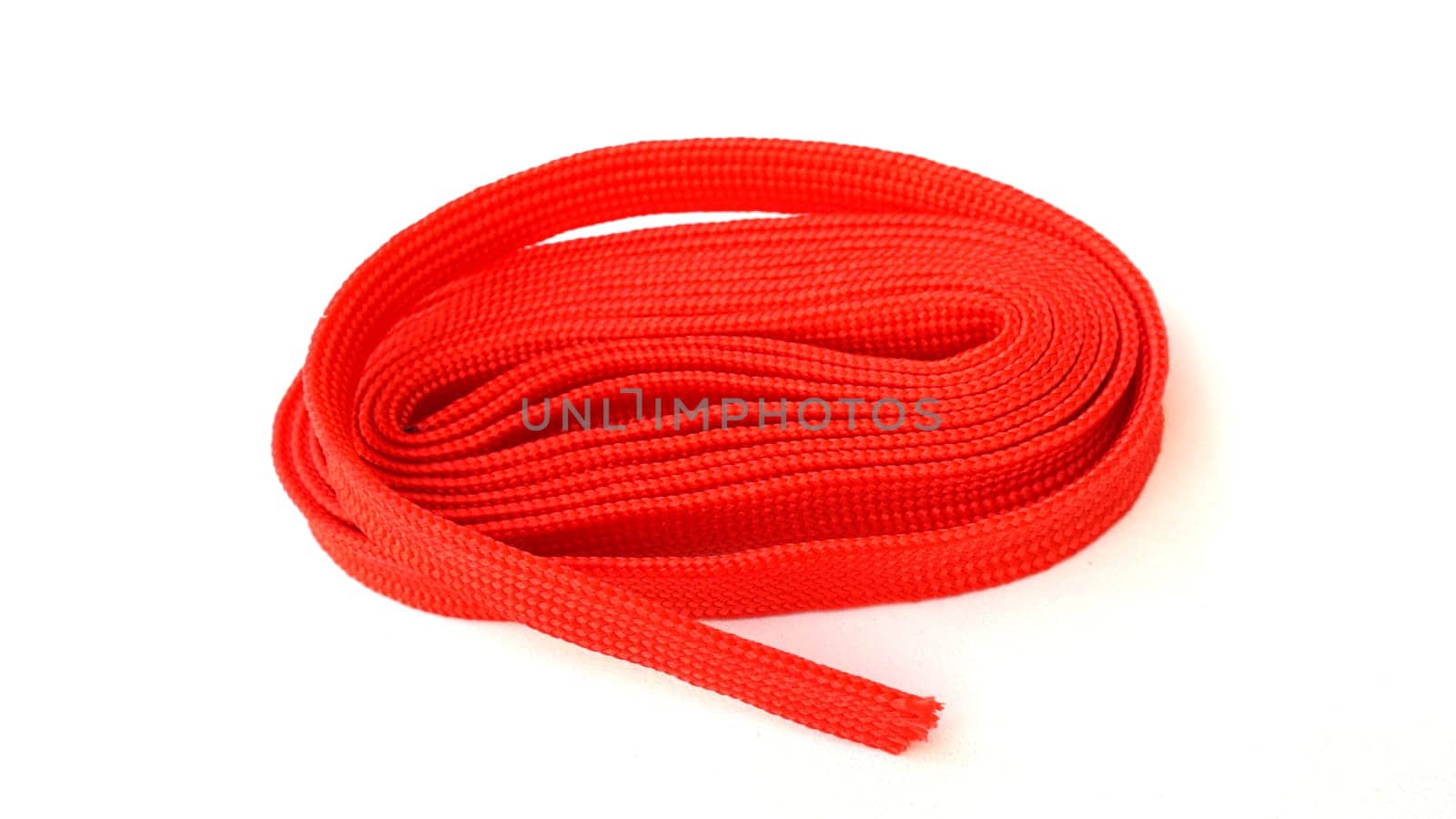 Red rope on white background. Fabric rope in red color folded in a coil.