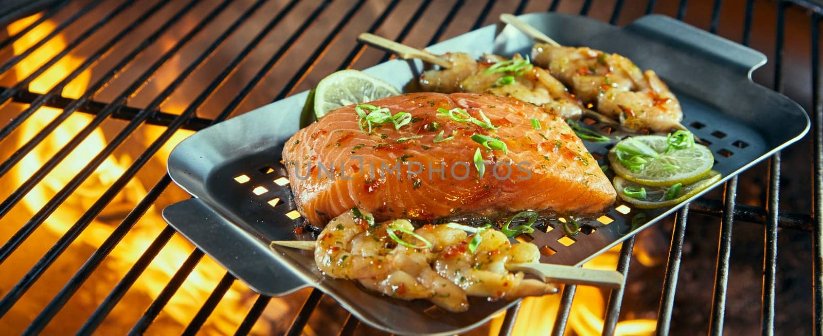 Fresh seafood for grilling over a barbecue with prawn kebabs and salmon steak ready seasoned wt herbs on a roasting pan