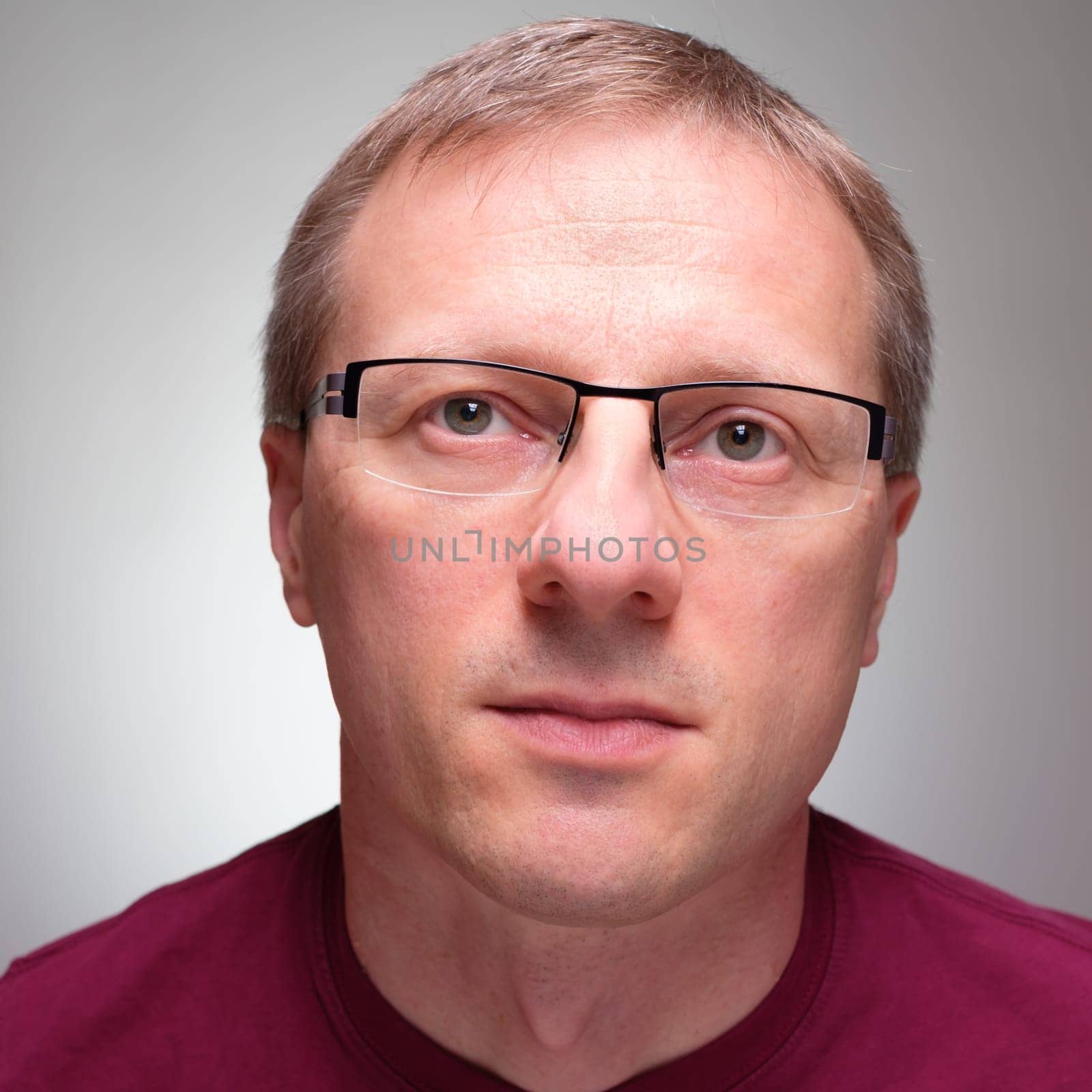 Man with glasses is looking up with expectation baclground grey