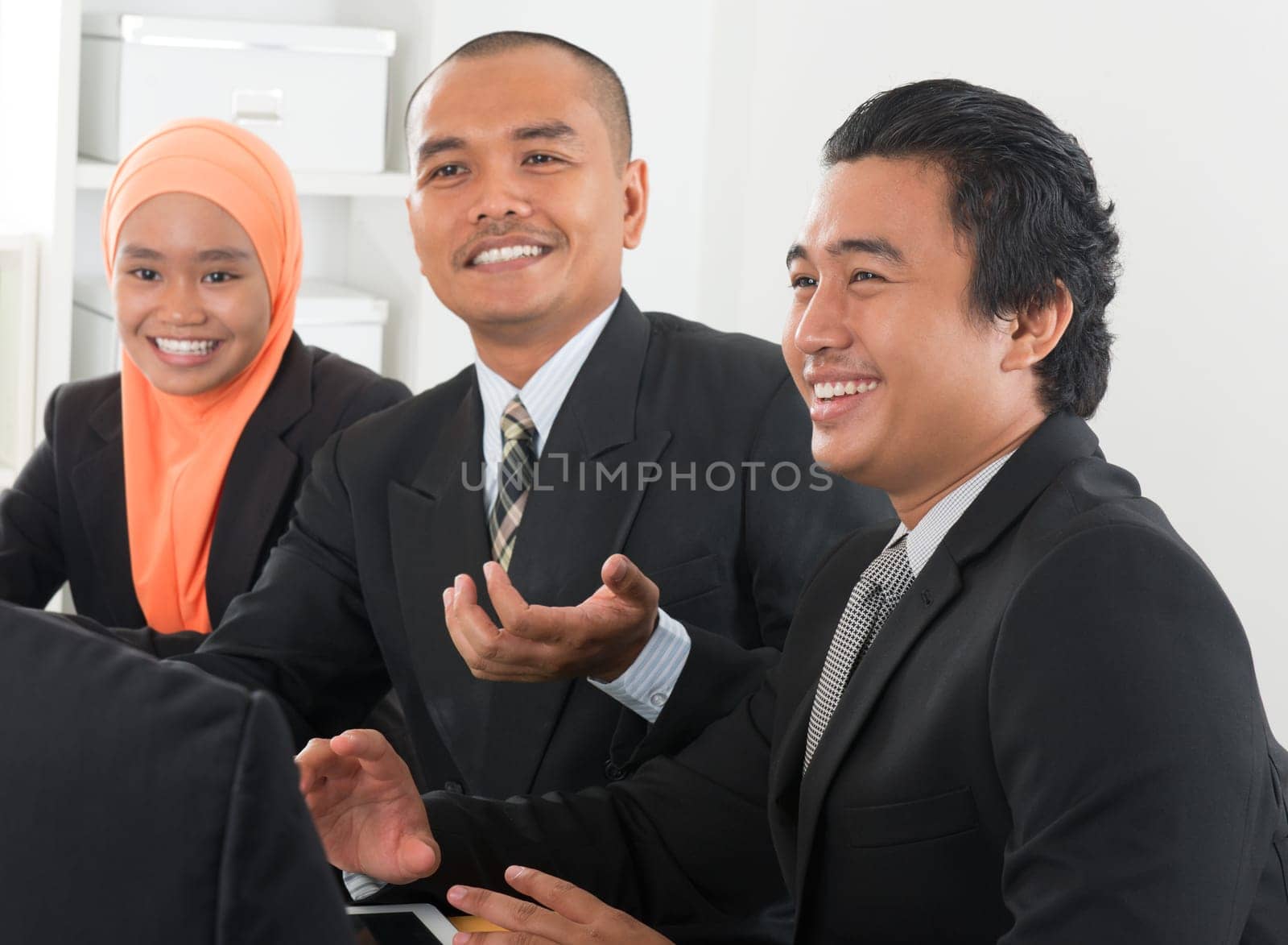 Group of Malaysian businesspeople meeting or having discussion on desk inside office room.