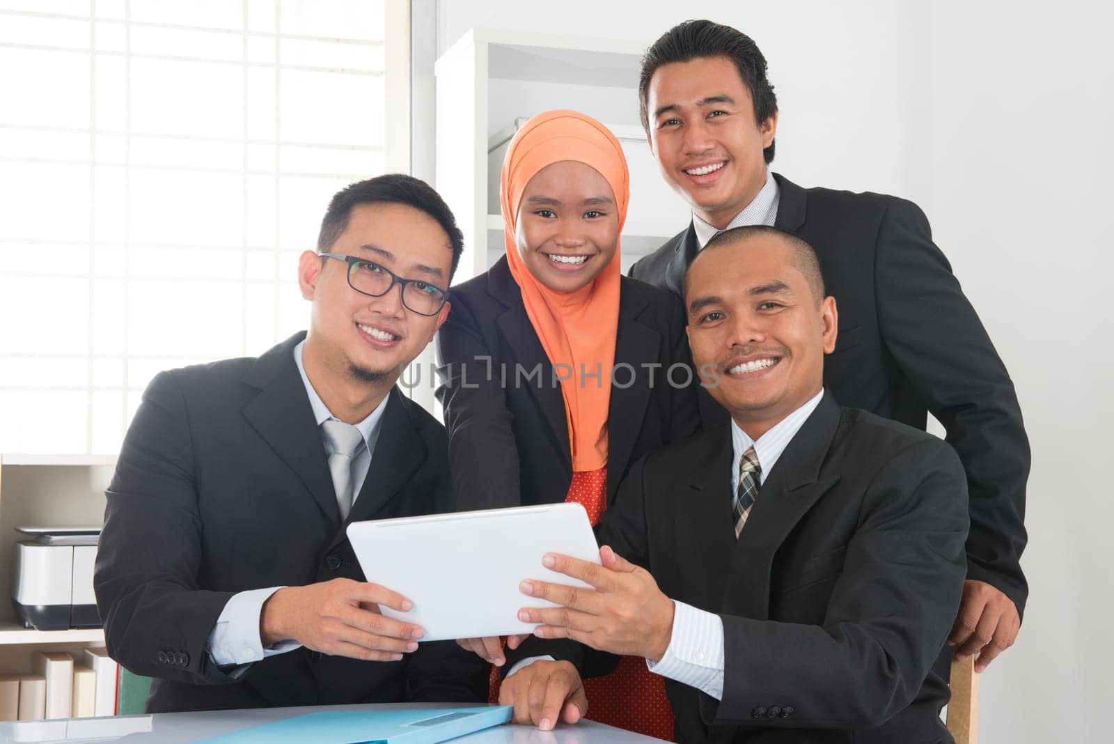 Group of Malaysian businesspeople meeting or having discussion on desk inside office room.