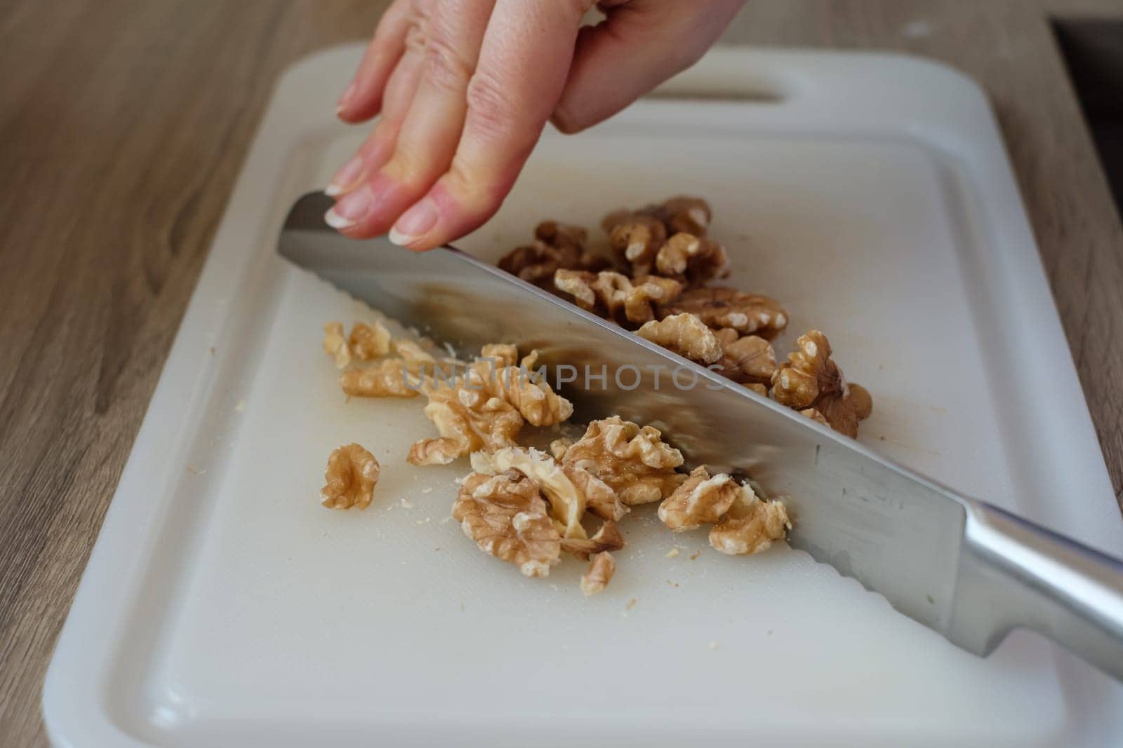 Female hand is hacking walnuts with a kitchen knife