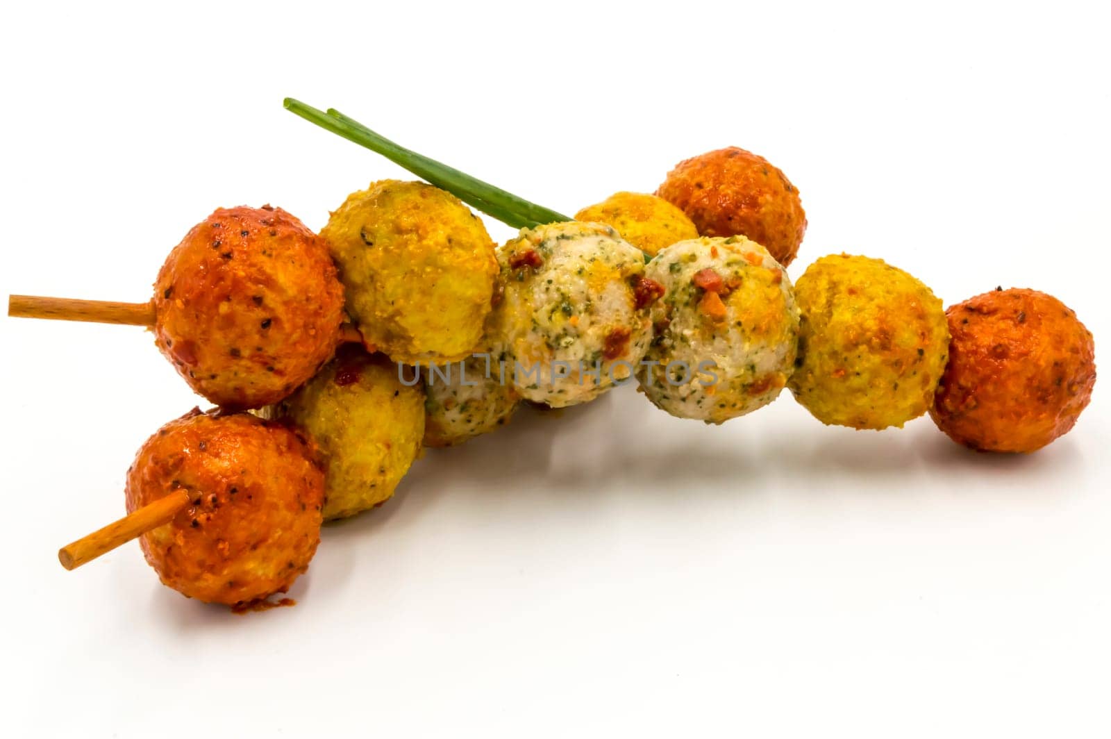 Marinated meatballs skewers on a wooden pick and a white background.