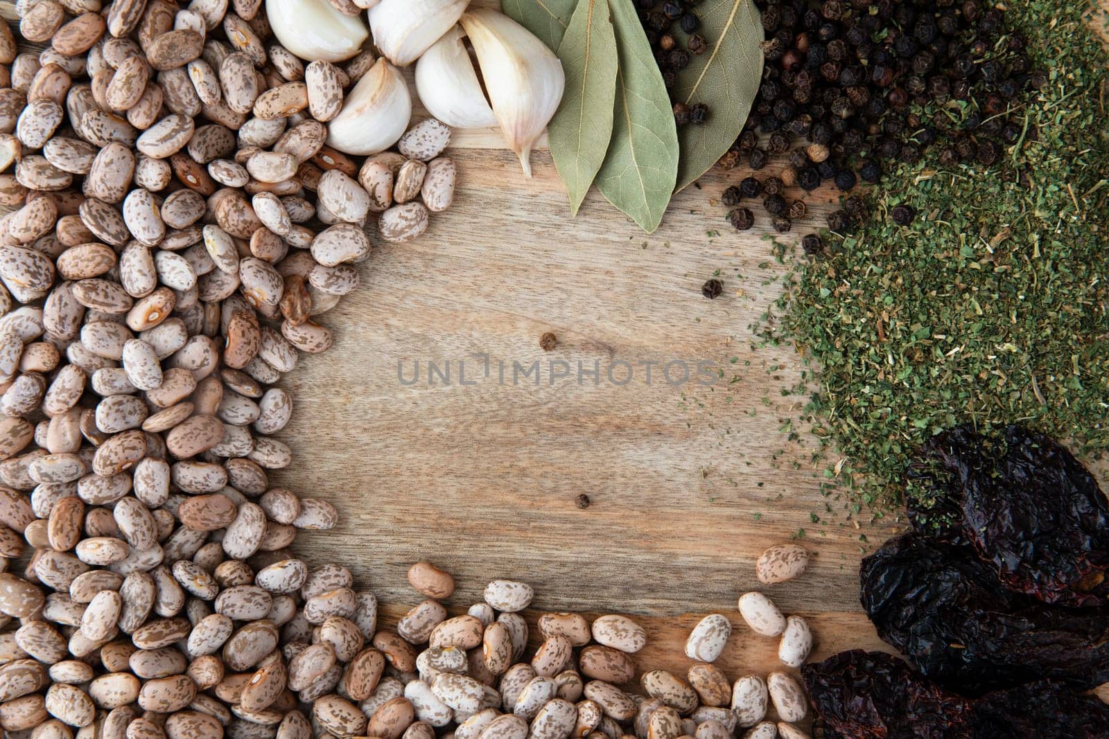 Flat lay of pinto beans, garlic, bay leaves, peppercorns, dried epazote and poblano peppers.