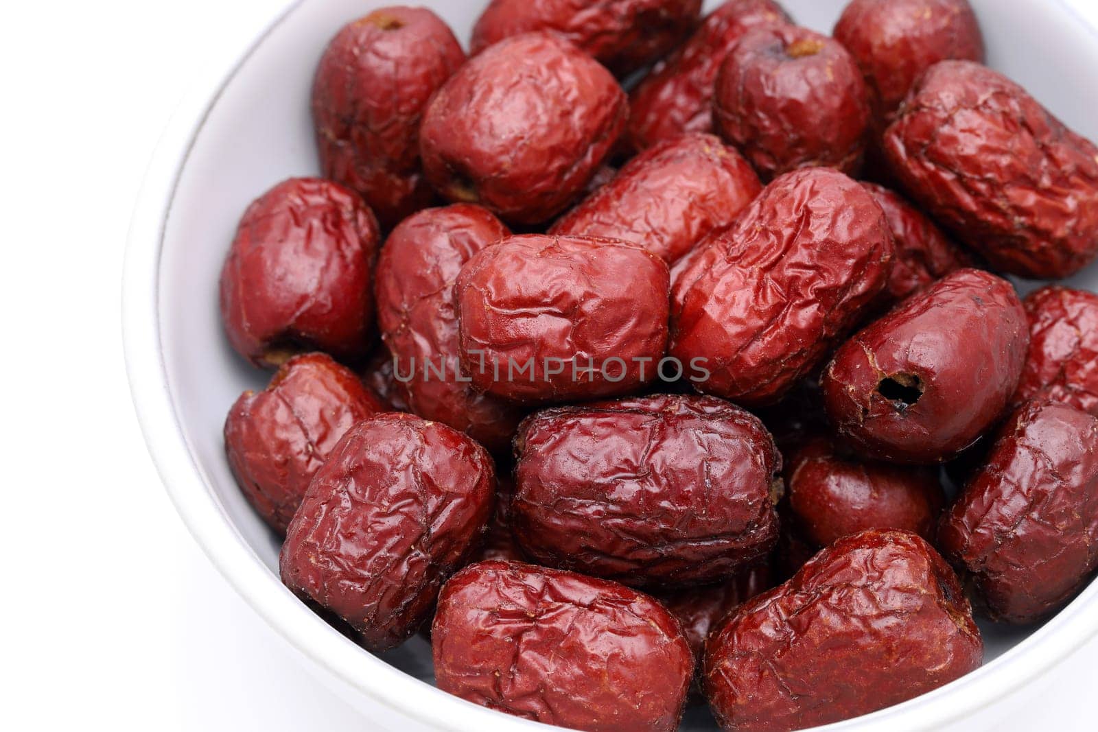 dried jujube fruits in a bowl, chinese herbal medicine on white background