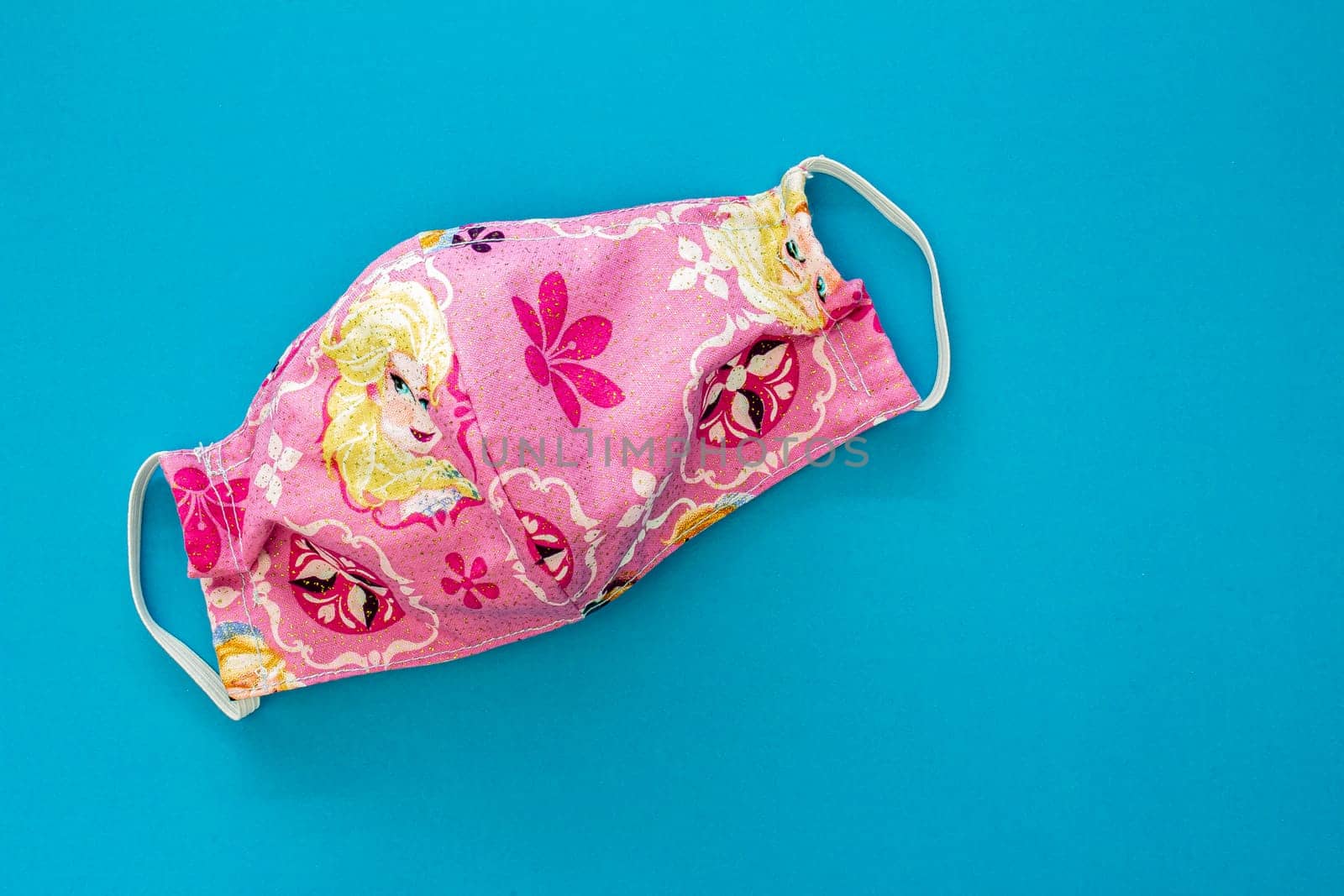 Pink homemade face mask for kids on a blue background