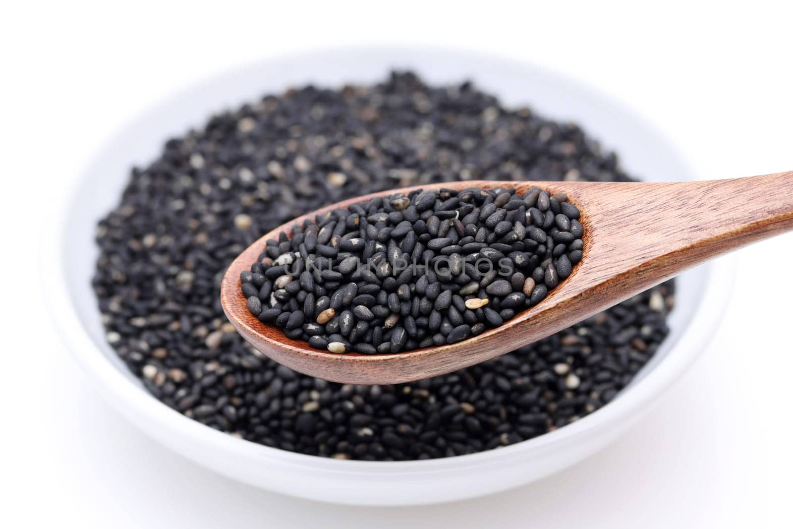 Black sesame seeds with wooden spoon. Sesame seeds in a dish