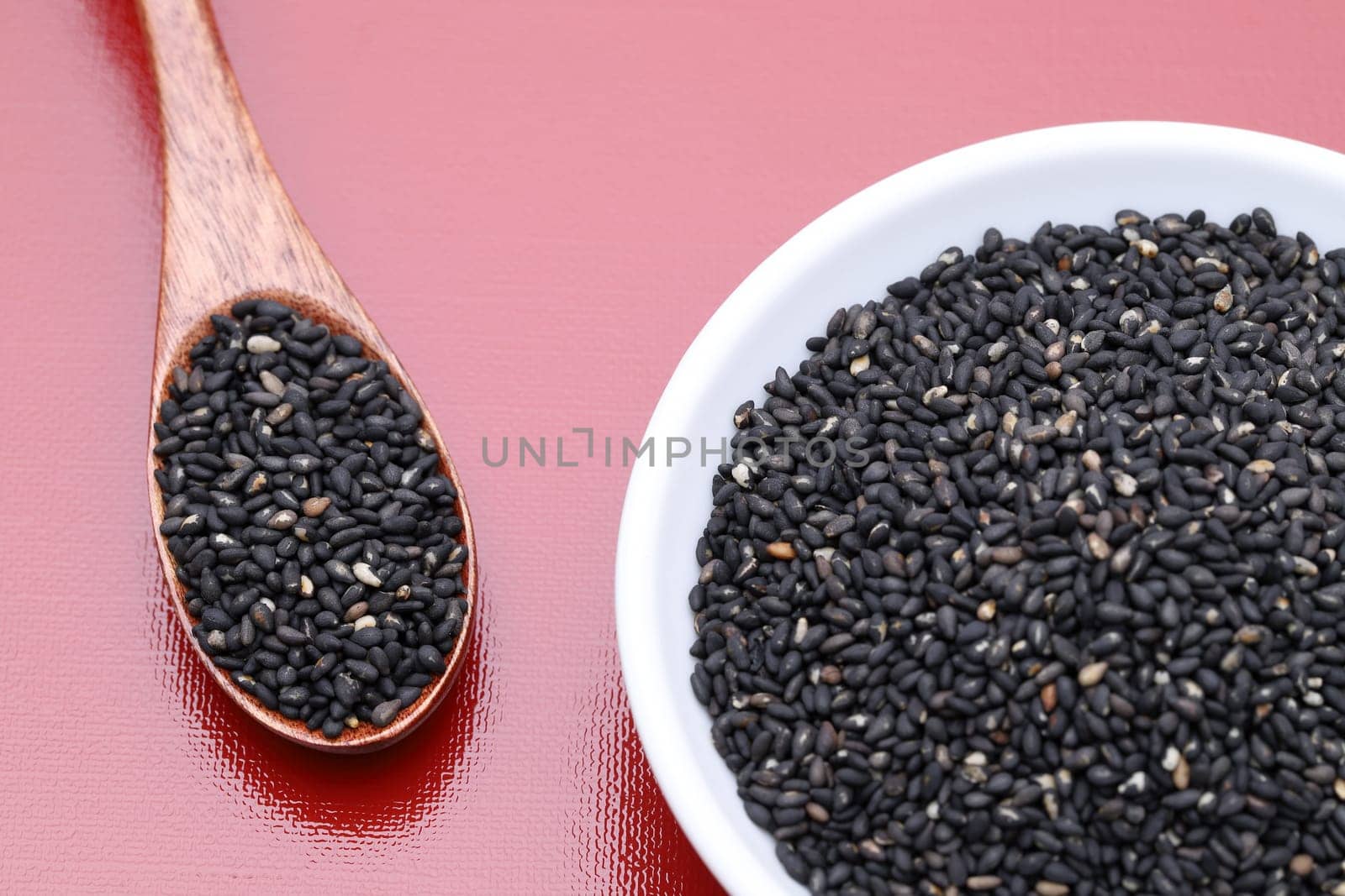 black sesame seeds in a dish with wooden spoon on table