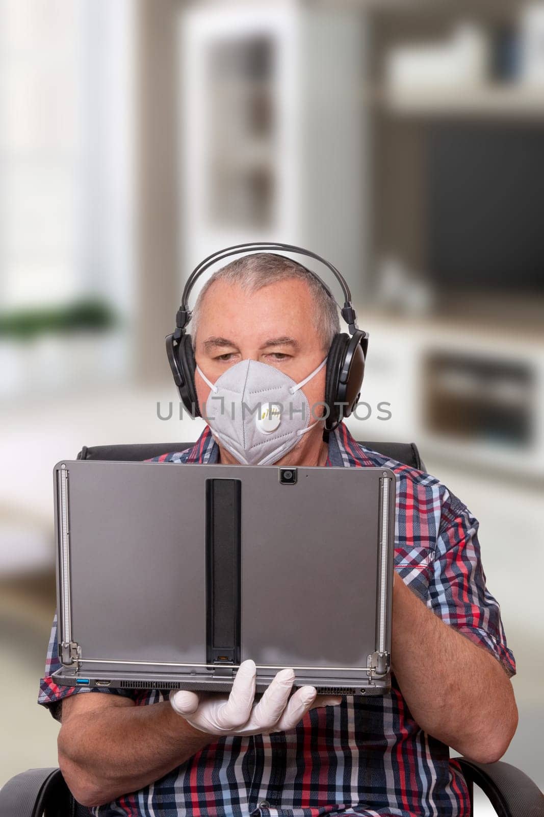 Coronavirus quarantine concept. A Business man stay at home working in home office on laptop and wearing protective mask and medical gloves. Avoiding social contact and distance. Protect against Covid-19.
