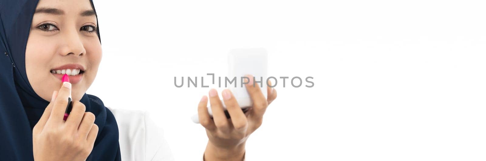 Young Muslim woman hold cosmetic and looking to camera to review product as vlog and blogger on white background taken in studio. Using for Fashion and beauty concept