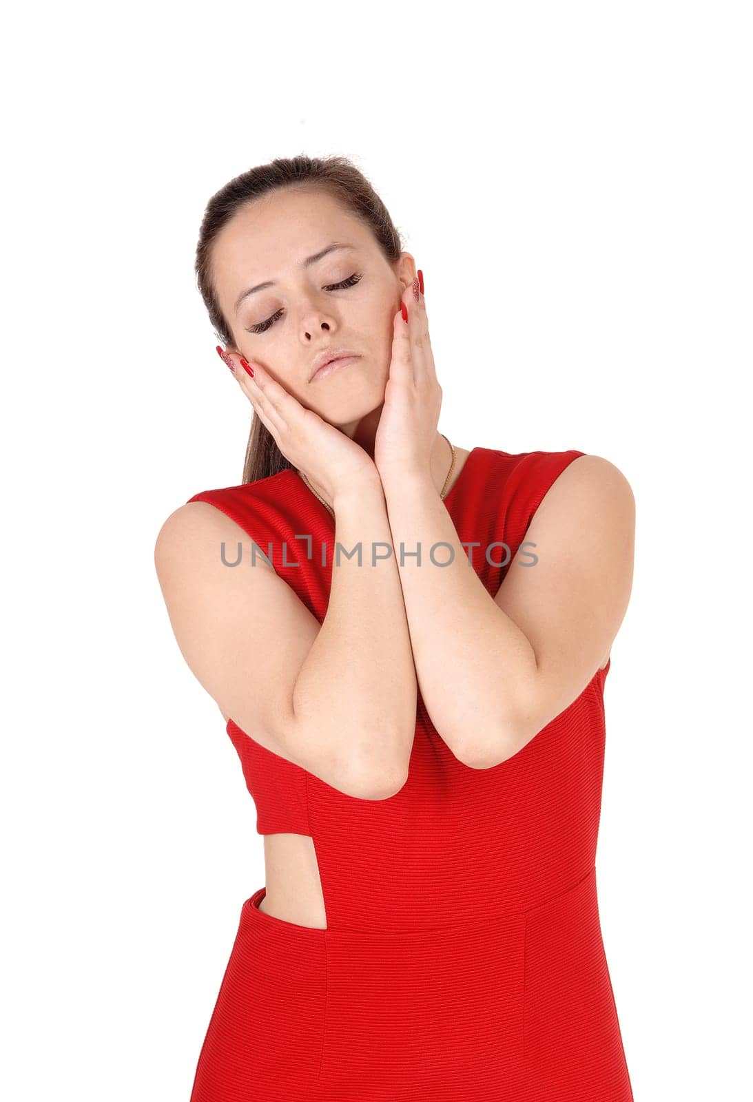 Young beautiful woman in a red dress standing with her hands on her.face and her eyes closed, isolated for white background.