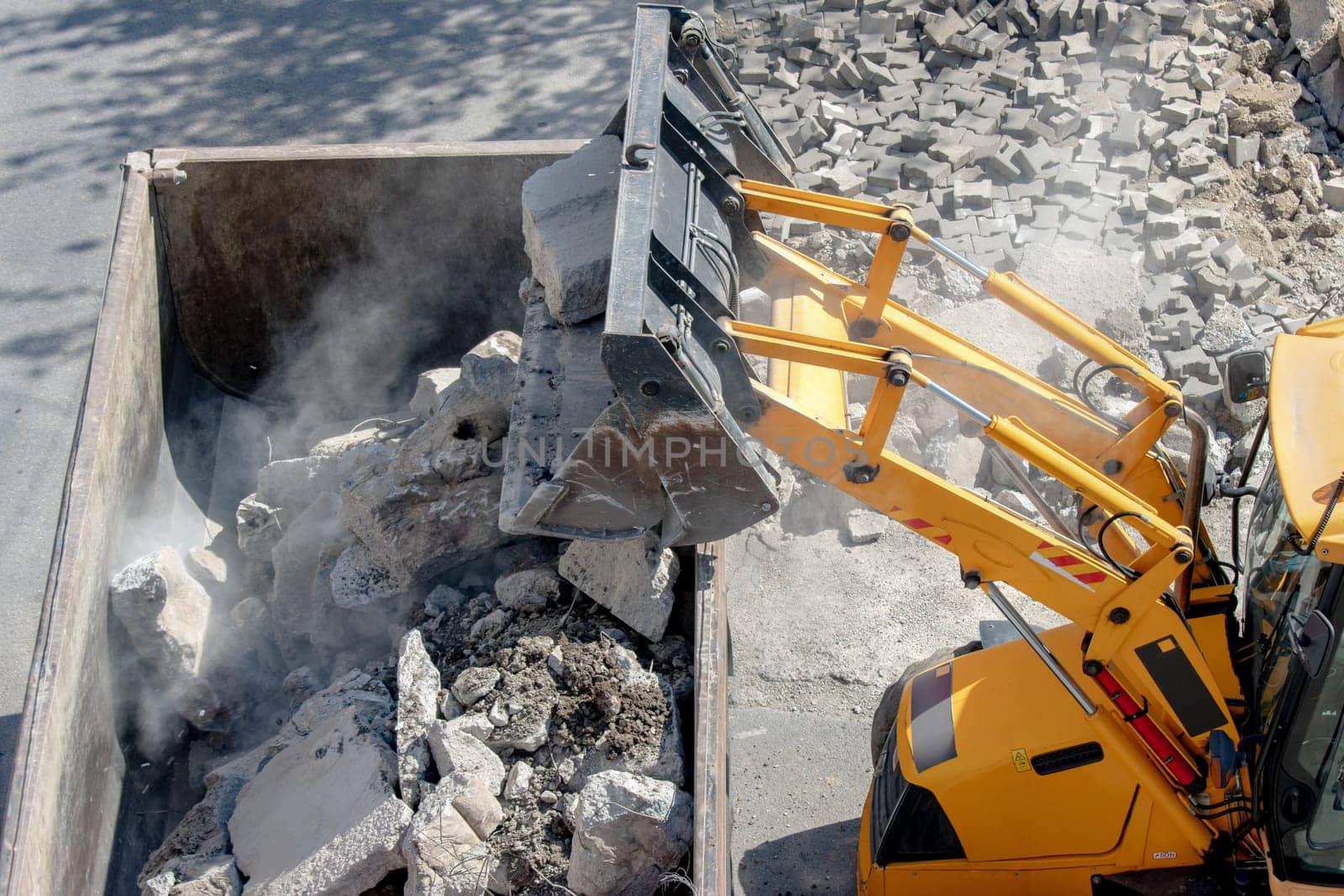 Bulldozer loader uploading concrete debris into dump truck at construction site