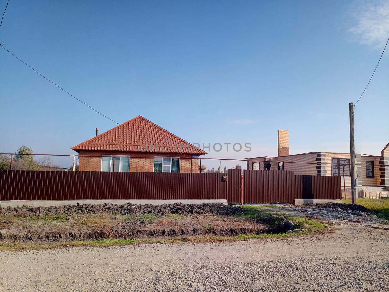 A new house with an orange roof and a brown fence.