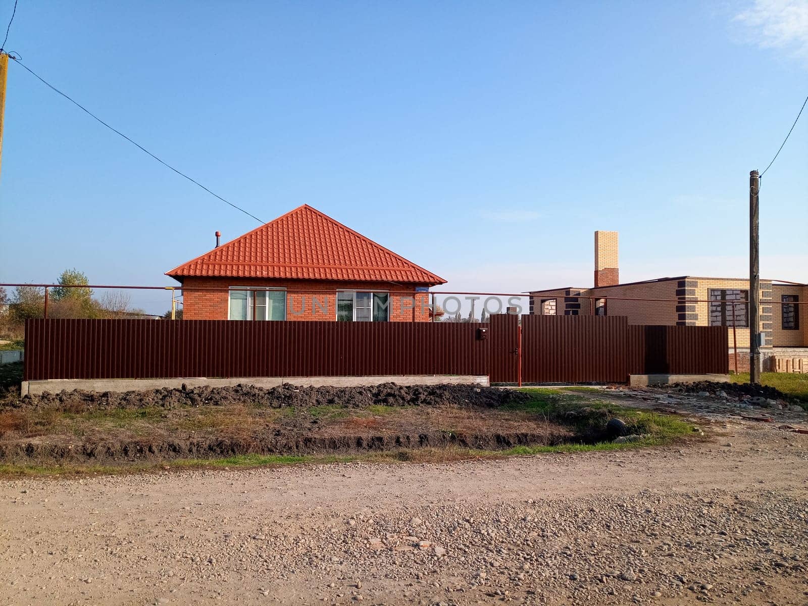 A new house with an orange roof and a brown fence.