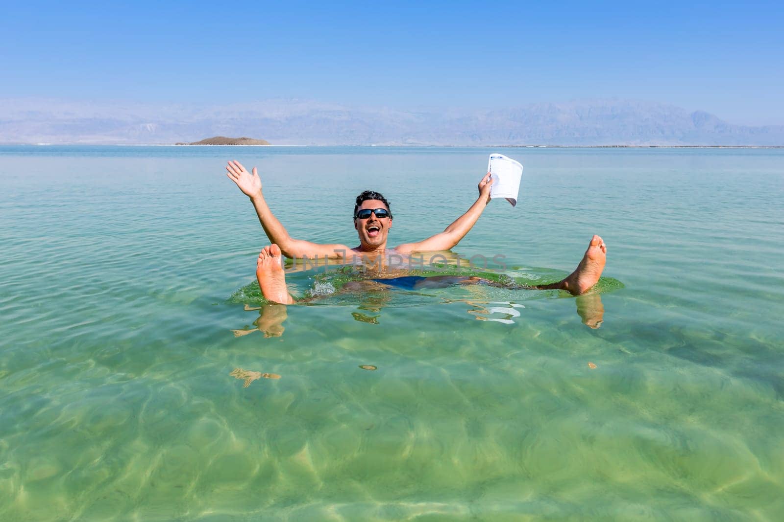 Man with open arms. Dead Sea coastline. Salt crystals at sunset. Texture of Dead sea. Salty sea shore