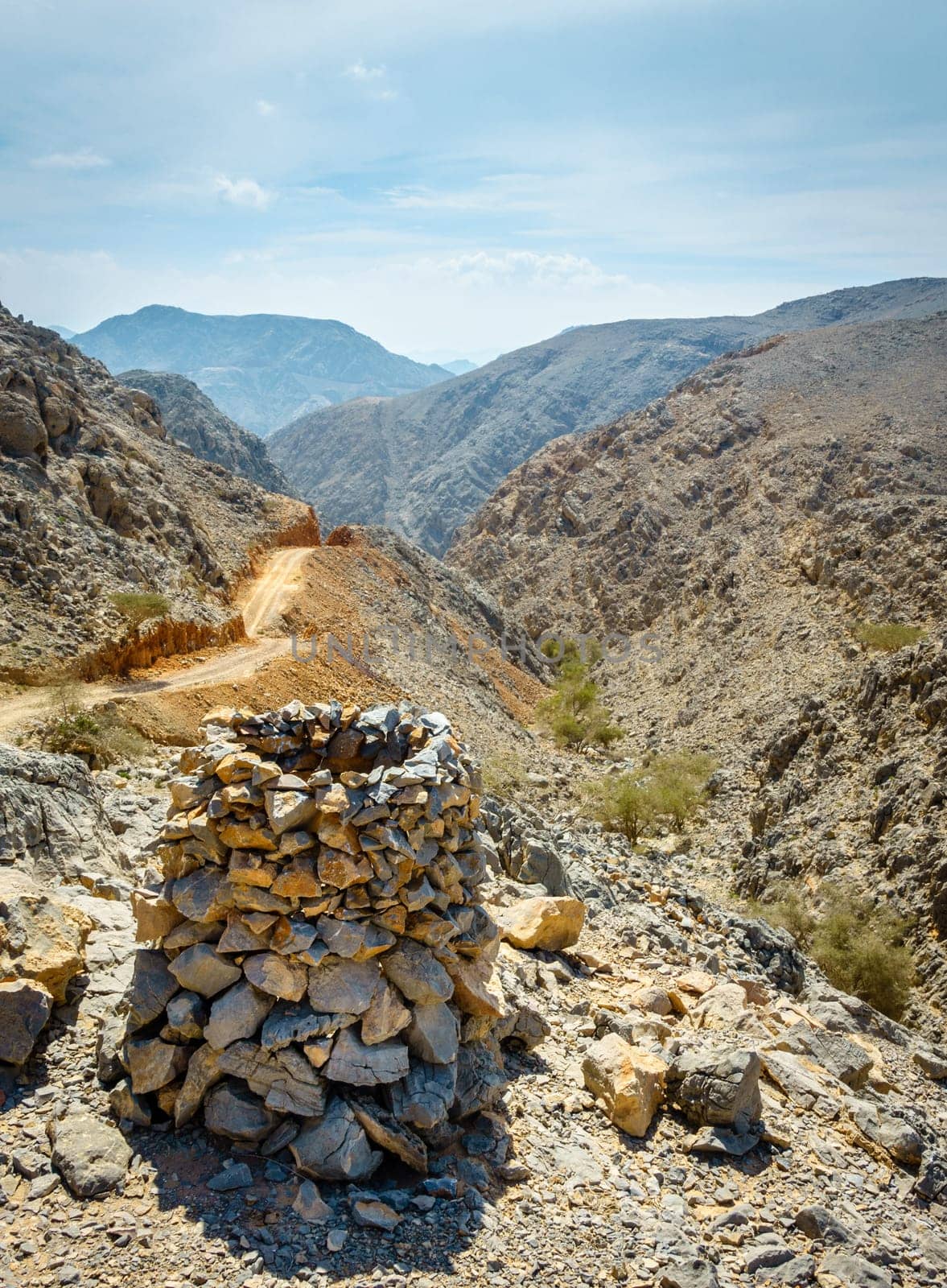 Dirt road in Al Hajar mountains in Fujairah, UAE with a rock pyramid in the foreground