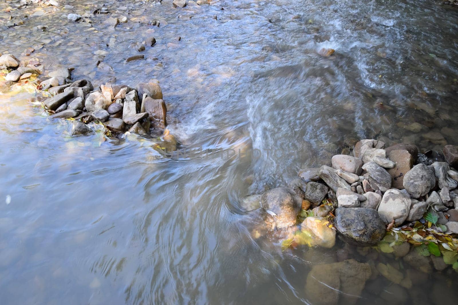 The flow of water on the doorstep in a mountain river. A shallow mountain river, the bottom of a mountain river of stones and gravel.