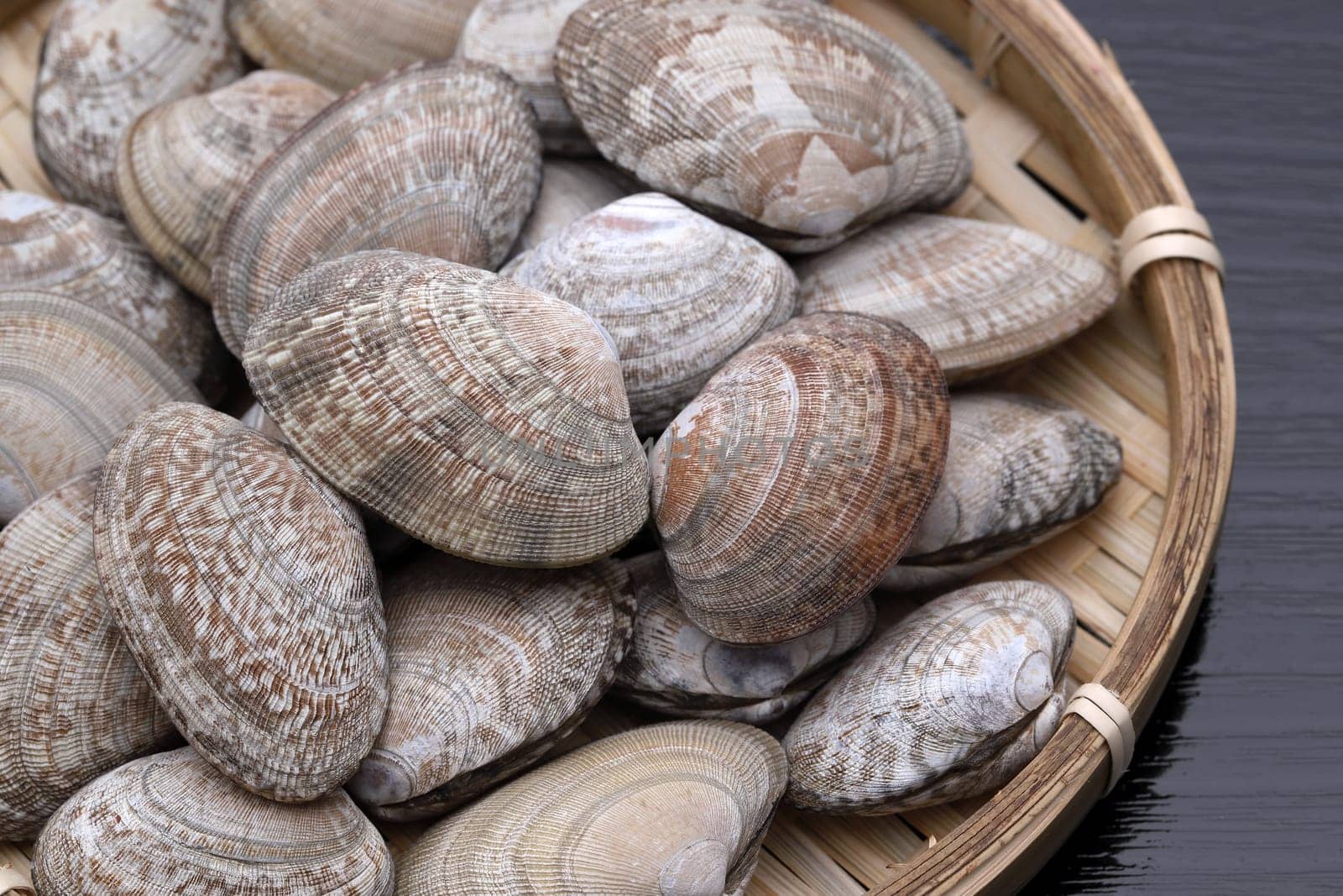 Japanese asari clams in a bamboo basket on wooden table
