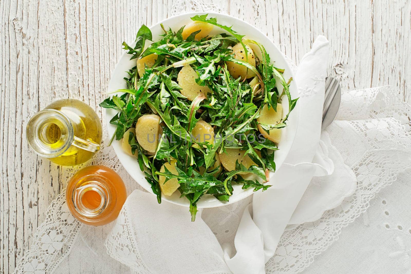 Healthy dandelion salad with potatoes on wooden background close up