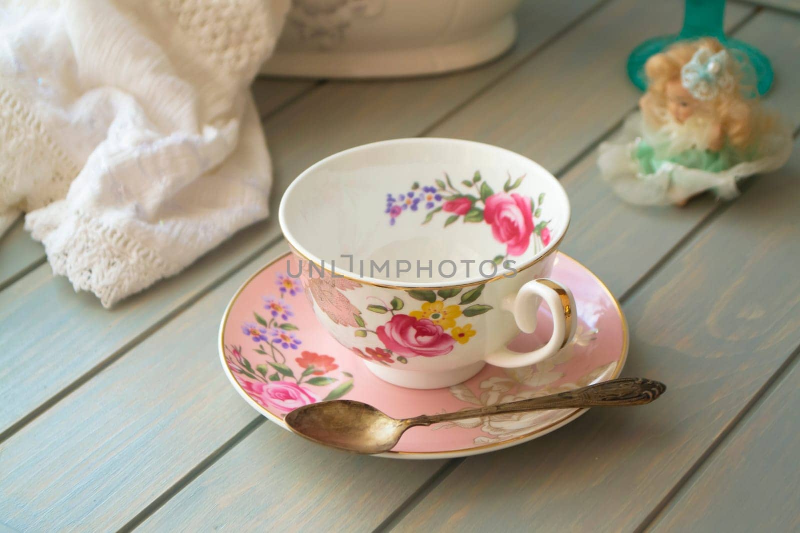 Pink vintage porcelain tea cup on turquoise table.