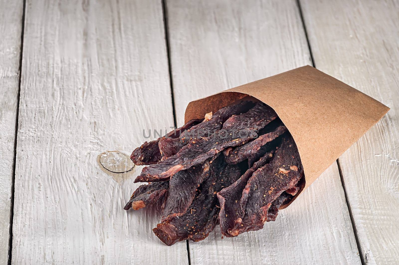 Jerky in a paper bag on top on white table