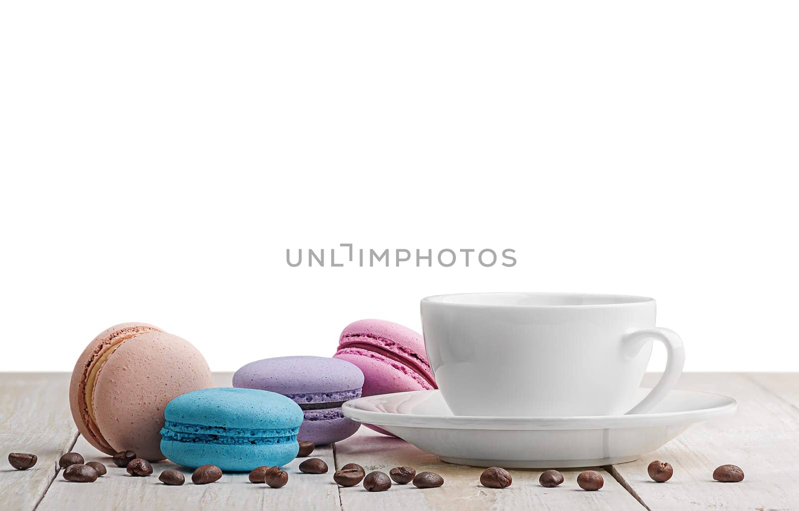 Macaroons with coffee on a wooden table with coffee grains on white background