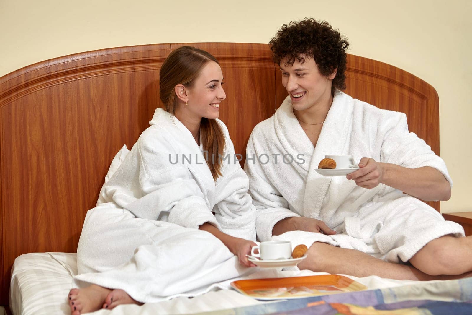 Happy young family  with breakfast lies in the bed at home.