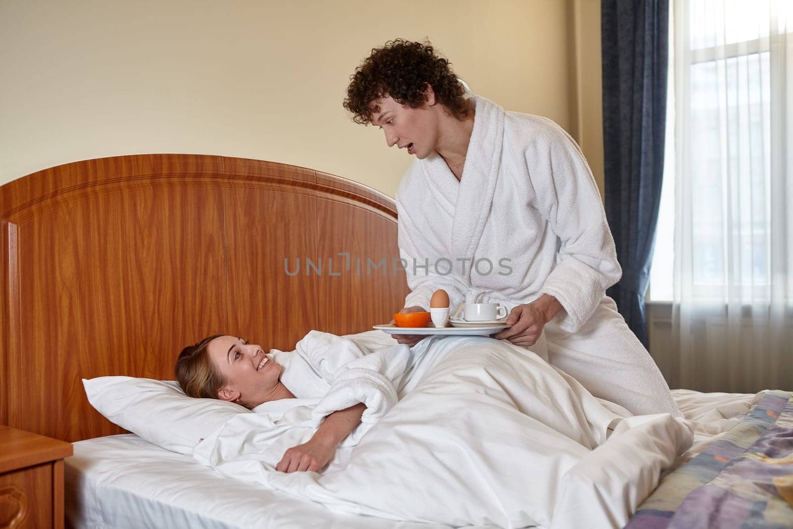 Happy young family  with breakfast lies in the bed at home.