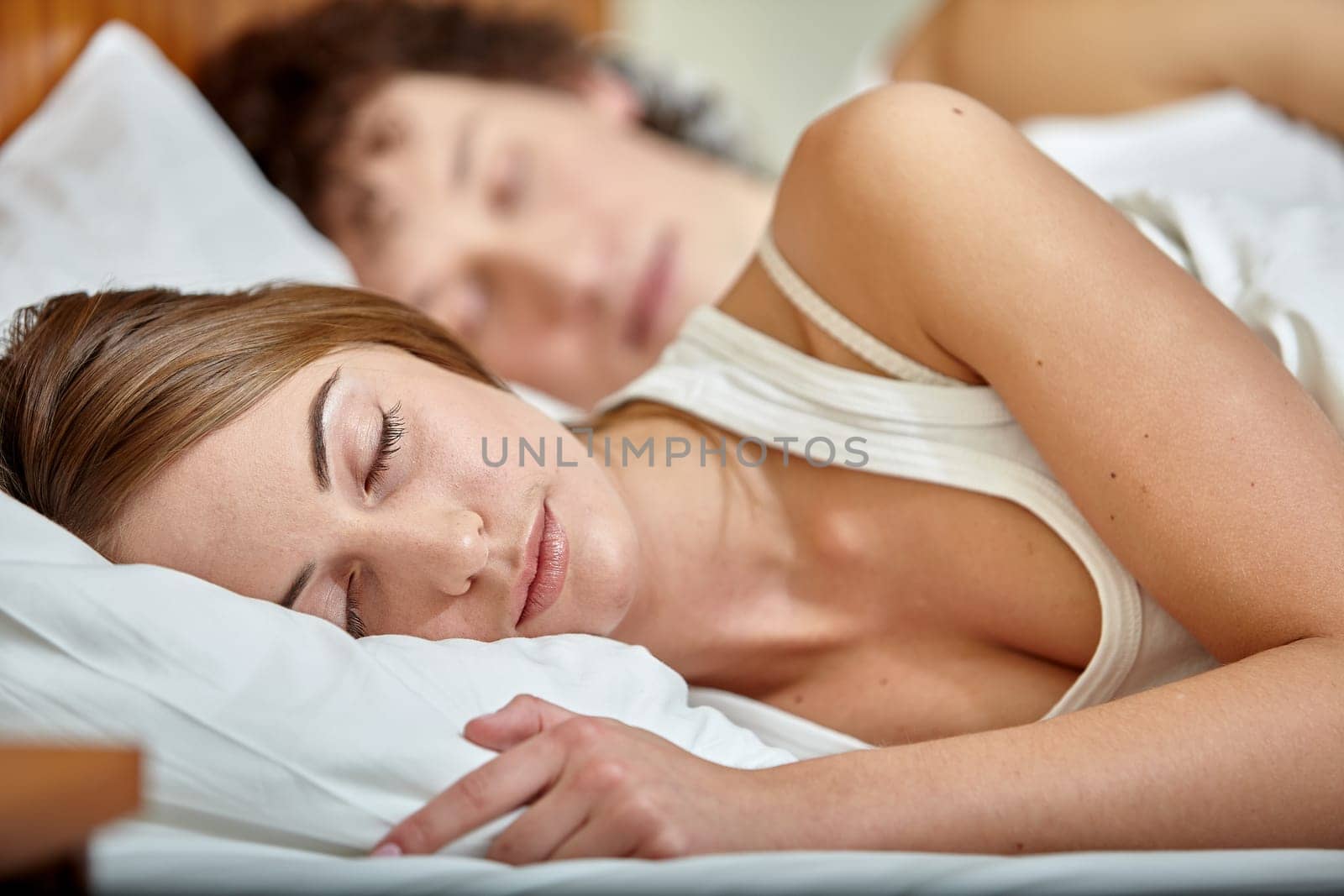 Happy young family sleep in the bed at home.  Selective focus on woman.