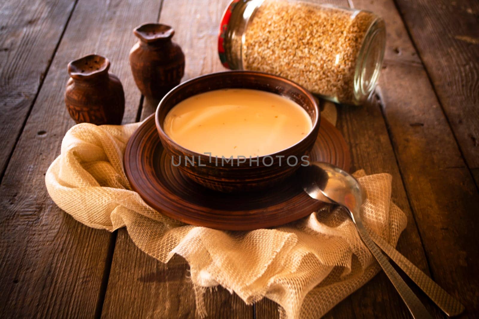 Boiled buckwheat with milk in wooden bowl on rustic wooden table