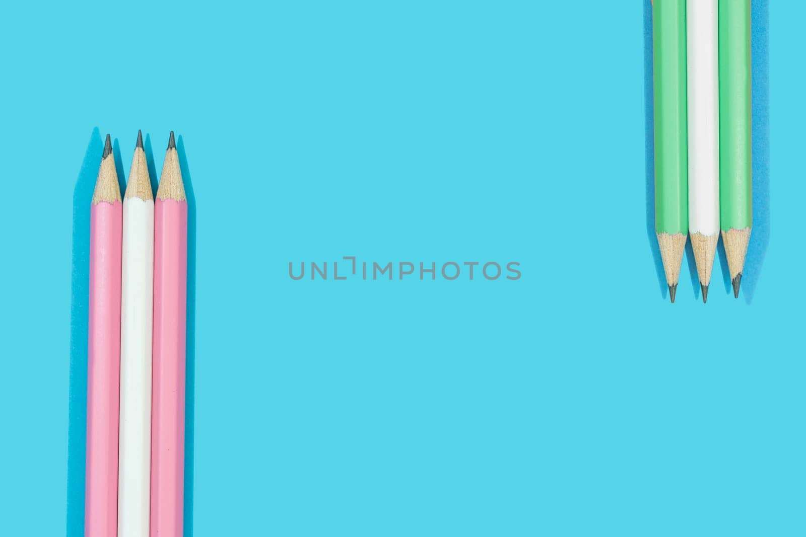 Pencils of pink, white and green on blue background.  Concept education stationery.